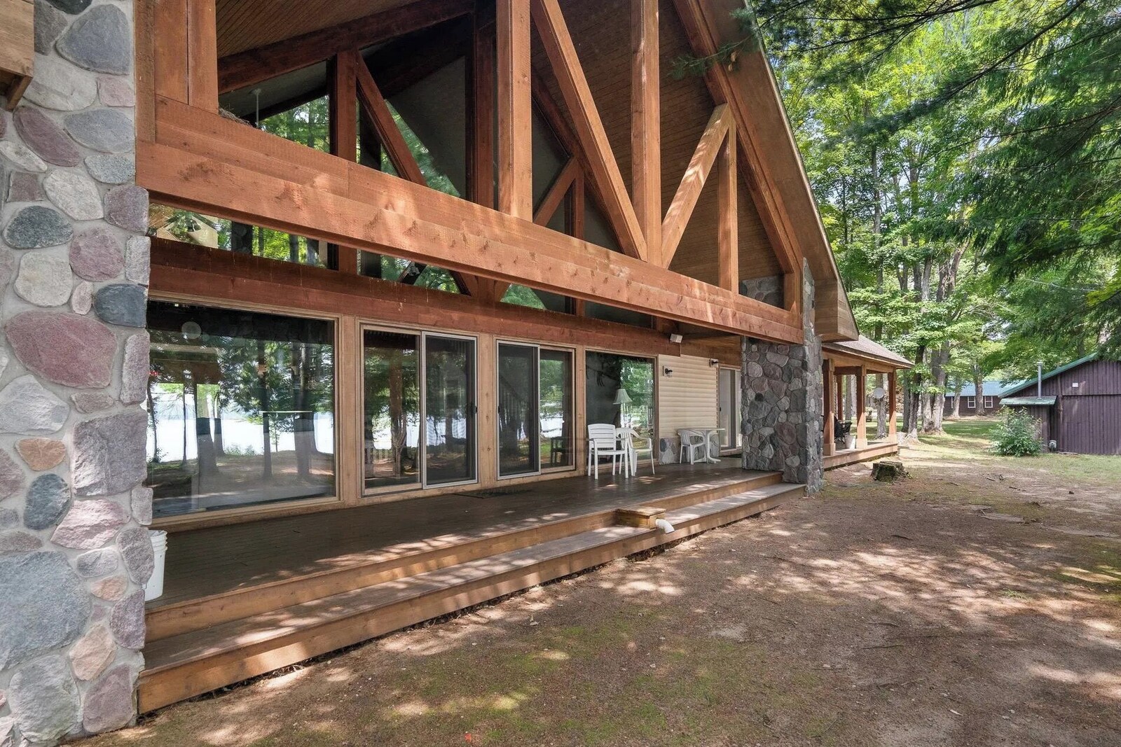 Bear’s Den Lodge with a broad deck and outdoor seating beneath mature trees